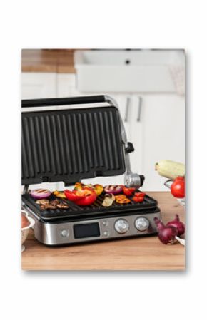 Tasty vegetables on modern electric grill on table in kitchen