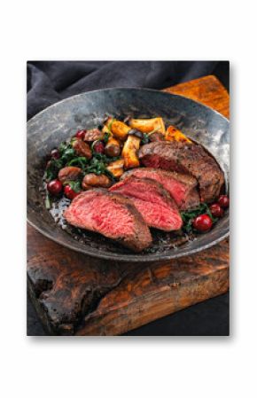 Barbecue dry aged beef steak - roast beef medium roasted, sliced with wild mushrooms, chestnuts, greens and cranberries in iron skillet pan