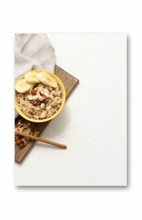 Bowl with tasty oatmeal, banana and nuts on white background