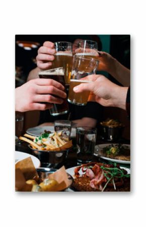 friends hands cheers beer together in a restaurant with food