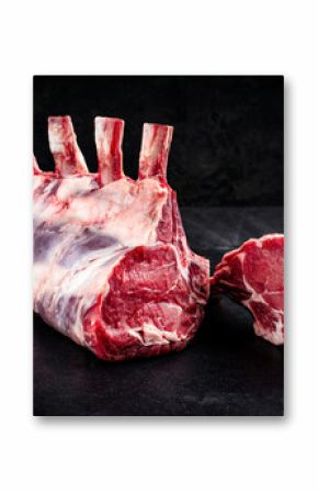 Raw dry aged bone-in back rack of veal loin offered as close-up on a black board