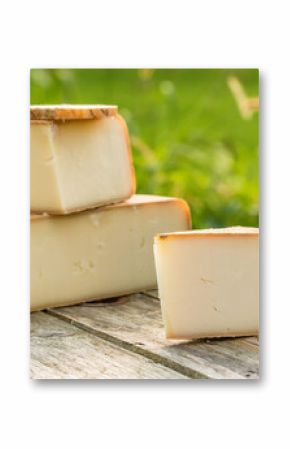 Traditional Ossau-Iraty cheese on a wooden table in the rural setting in France.