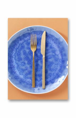 Empty plate and cutlery on light orange background, top view