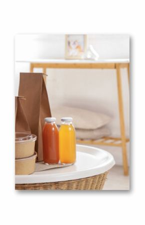 Paper bags with containers and juice on table in living room, closeup. Food delivery service