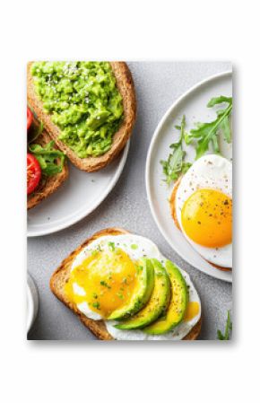 Delicious flat lay of brunch spread with avocado toast, fried eggs, fresh arugula, cherry tomato, and cup of black coffee
