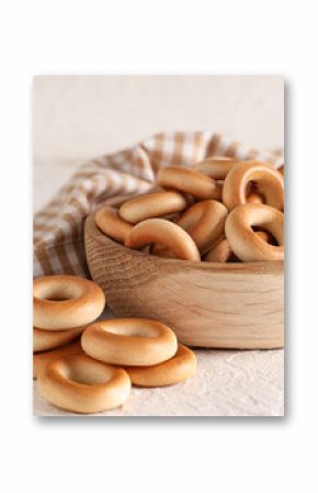 Wooden bowl of tasty bagels on light background