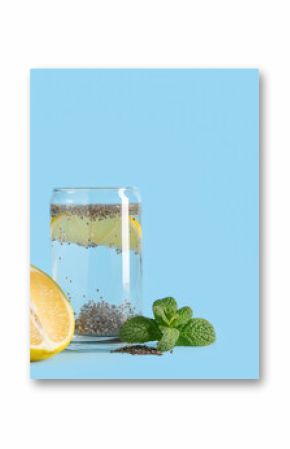 Glass of water with chia seeds, lemons and mint on blue background