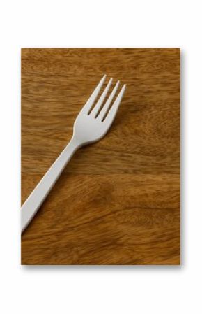 Disposable white plastic fork placed on a wooden table