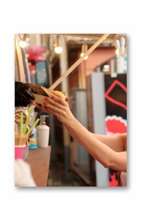 Joyful young blonde woman exchanges cash for food at lively outdoor market food truck with string stringlights, warm glow creating friendly, festive atmosphere