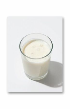 Glass of creamy milk with frothy top on white background. High angle view of refreshing dairy beverage. Minimalist, clean studio shot of healthy drink. Great for breakfast, smoothies, or recipes.