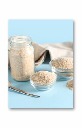 Jar and bowls with psyllium husk powder on blue background
