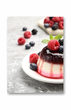 Tasty panna cotta with berries and jam on light grey table, closeup. Space for text