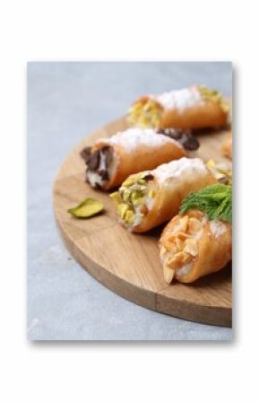 Delicious cannoli with cheese, nuts, powdered sugar, chocolate and mint on grey table, closeup. Space for text