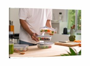 Man preparing healthy homemade meal prep in food container with fresh food at home.