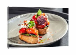 Bruschetta with roasted vegetables, pesto, and cream cheese on a ceramic plate. copy space