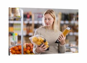 Young female shopper buying package of pasta in grocery store