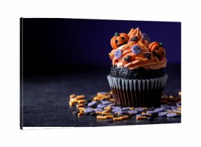 Halloween cupcakes with Halloween sprinkles on black surface and purple background. Copy space