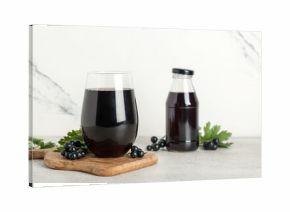 Glass and bottle of fresh black currant juice on white background