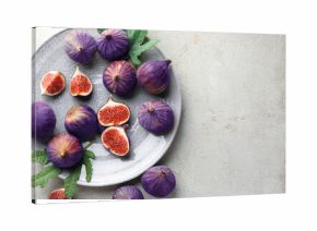 Fresh ripe figs and green leaves on gray textured table, flat lay. Space for text