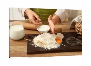 Woman sifting flour for preparing dough on kitchen counter