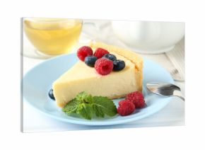 Piece of delicious cheesecake with fresh berries and mint served on white wooden table, closeup