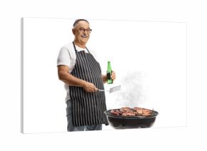 Man holding a turner utensil and a bottle of beer and grilling meat on a barbecue