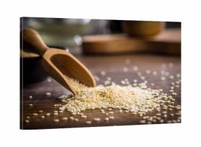 Roasted sesame seeds in scoop on wooden table.