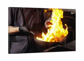 Male chef France flambe cooking in commercial kitchen with frying pan