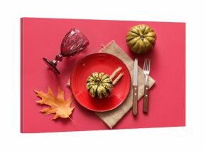 Beautiful table setting with pumpkins, wheat and autumn leaf on red background