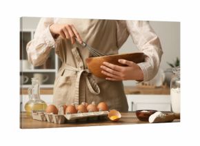 Woman mixing ingredients in bowl for preparing dough on kitchen counter