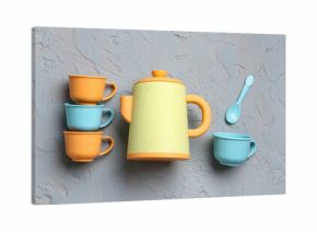 Teapot with cups and spoon for baby on grunge grey background