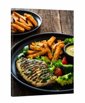 Grilled chicken breast, sweet potato fries with barbecue sauce and boiled broccoli on wooden table 