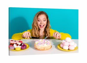 Young woman in a yellow sweater joyfully enjoys a colorful cake and pastries in a bright blue studio setting