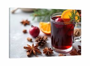 Warm mulled wine in glass mug with orange slice. Festive drink with cinnamon star anise berries pine cones, winter holiday season. Cozy Christmas beverage preparation for party.