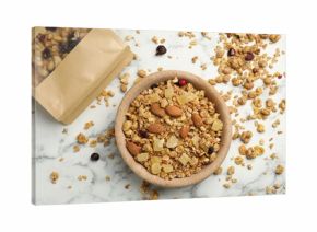 Tasty granola with dried fruits and nuts in bowl and paper bag on white marble table, flat lay