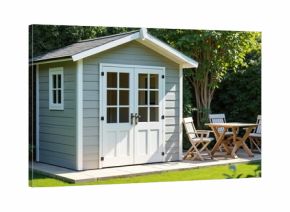 Modern grey garden shed with double doors and window, set in a green backyard. Wooden table and chairs placed outside on paved area. Perfect space for relaxation or storage needs.