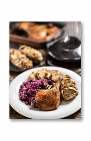 Portion of roast duck leg red cabbage homemade dumplings on plate and red wine on the background