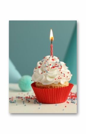 Birthday cupcake with burning candle and party cones on white table