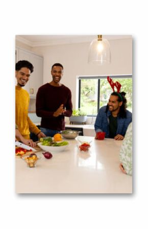 Christmas time, multiracial friends in kitchen preparing holiday meal, wearing festive hats, at home