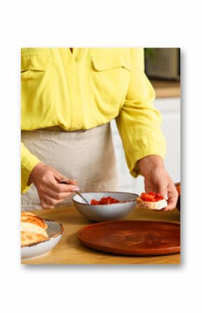 Young woman cooking tasty vegan bruschetta at table in kitchen, closeup