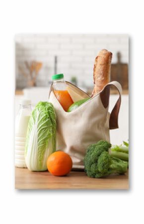 Grocery bag with different fresh products on wooden table in kitchen