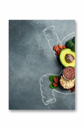 A set of fresh fruits, vegetables and nuts laid out in the shape of a stomach. A chalk drawing of a human stomach. The best foods for healthy digestion.