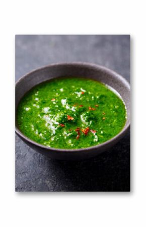 Chimichurri, green parsley and chili sauce in a bowl. Dark background. Close up.