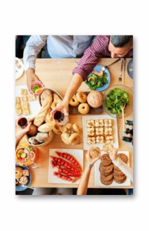 Top view of a diverse group enjoying a meal. People share food, toast drinks, and celebrate. A variety of dishes and drinks on a wooden table. Buffet table with delicious food photo from top view.
