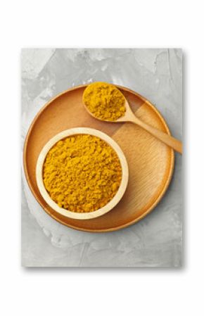 Turmeric powder in bowl and spoon on light grey table, top view