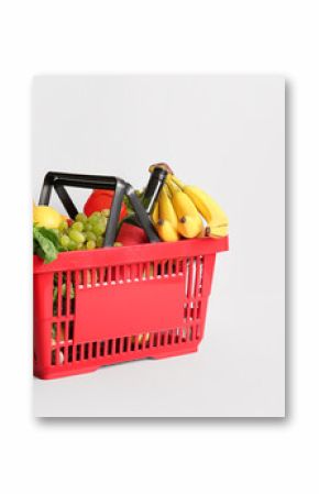 Red shopping basket full of different fresh products and baguette on white background