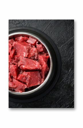 Bowl for a pet with fresh meat. On a black stone background.