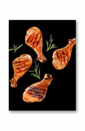 Grilled chicken legs or drumsticks falling down with herbs and colourful peppers isolated on black background. Juicy BBQ chicken drumsticks sprinkled with herbs and seasoning on black background..
