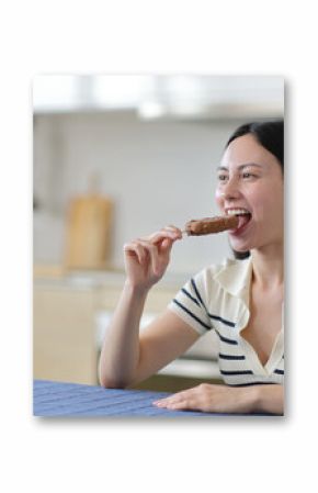 Asian woman biting chocolate ice cream in a kitchen