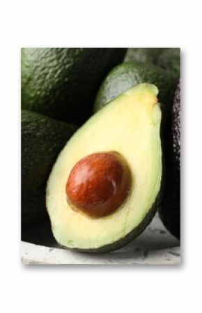 Whole and cut avocados on plate, closeup